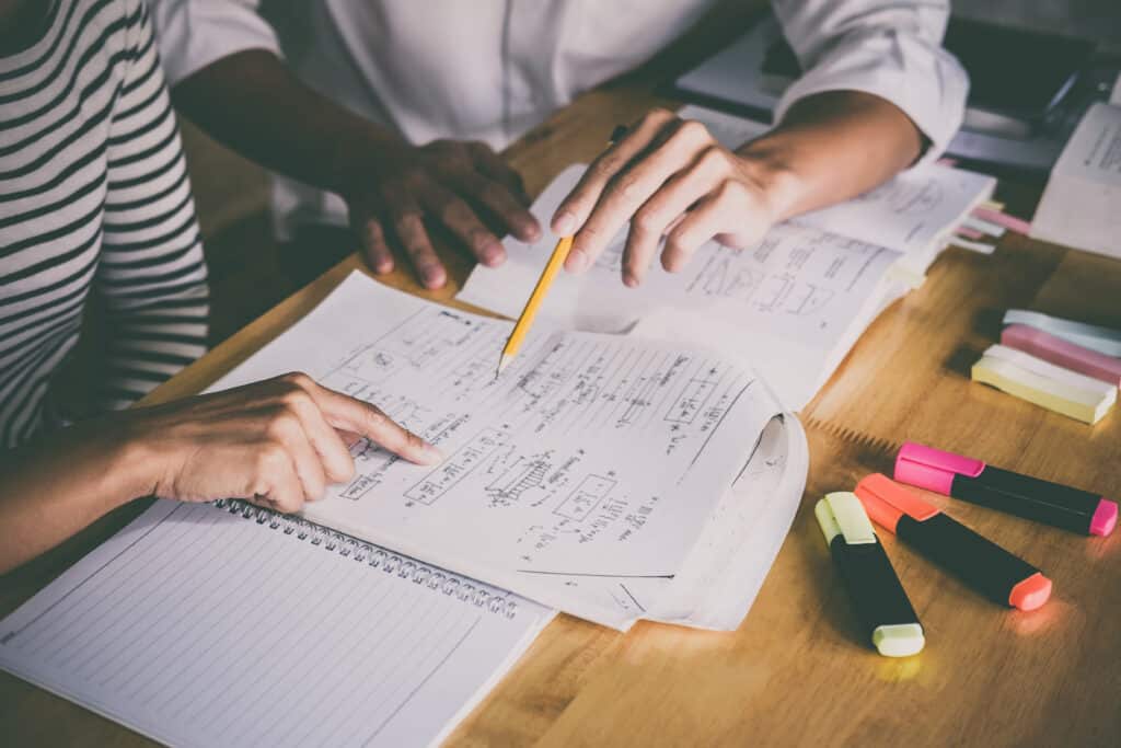 High school or college student group catching up workbook and learning tutoring in classroom and reading, doing homework and lesson practice preparing exam.